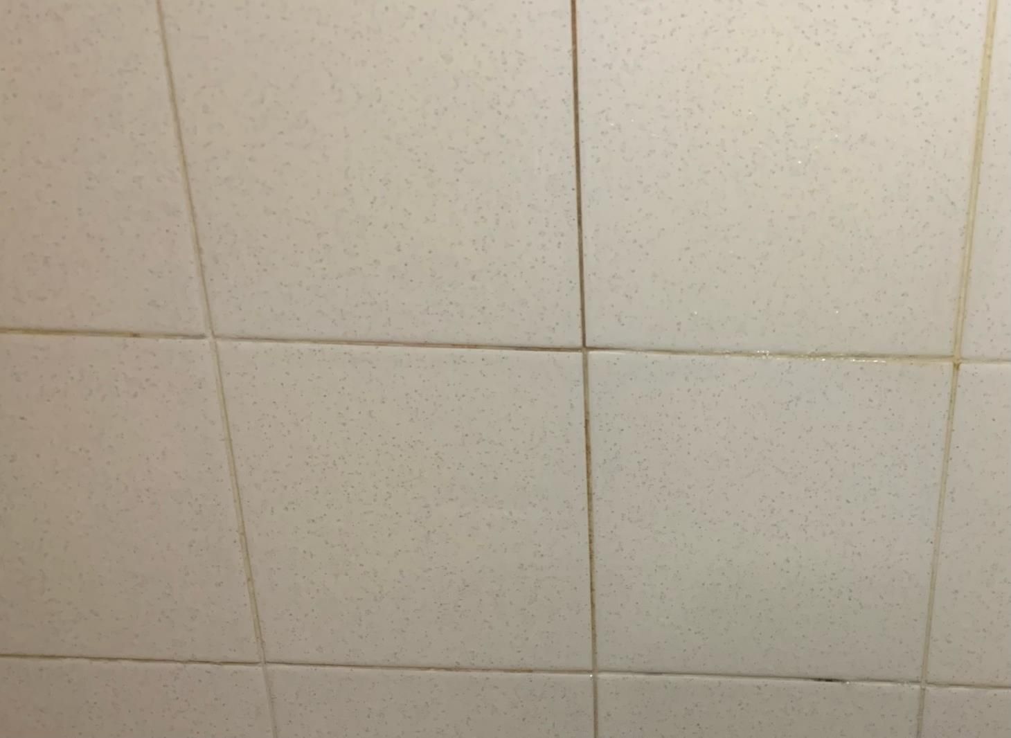 A close up of a bathroom wall with white tiles
