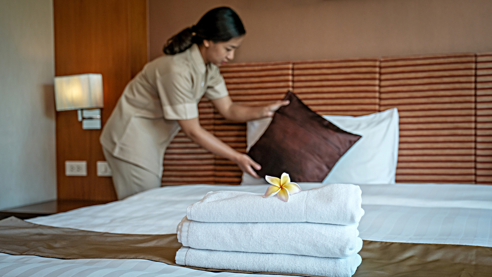 A maid is making a bed in a hotel room.