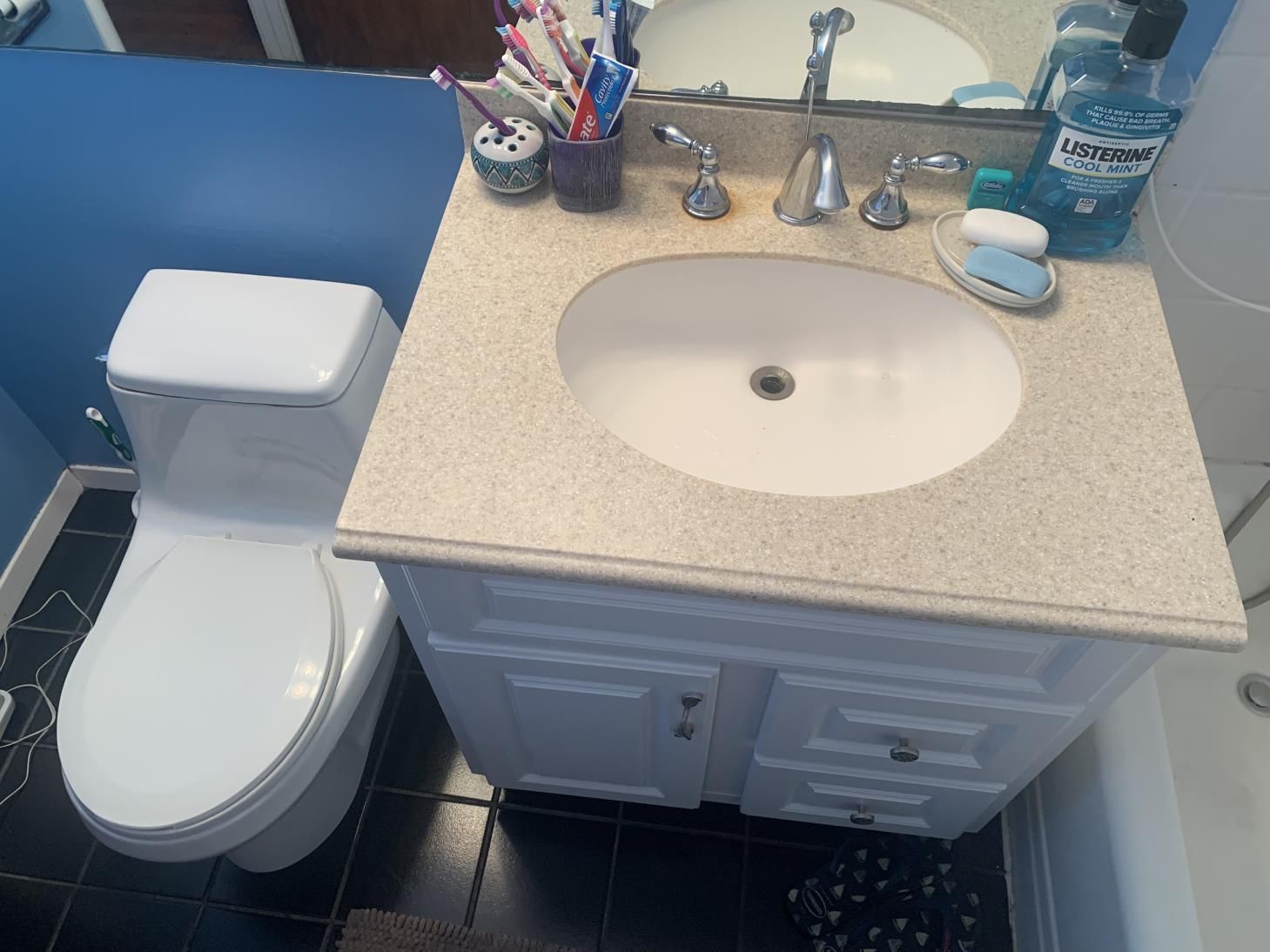 A bathroom with a toilet , sink and mirror.