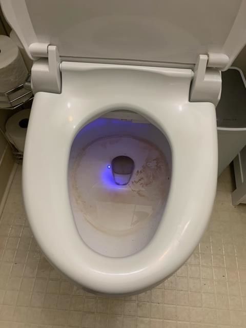 A close up of a toilet with a blue light on it.