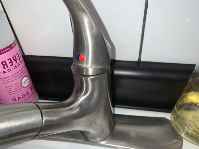 A faucet with a bottle of soap next to it