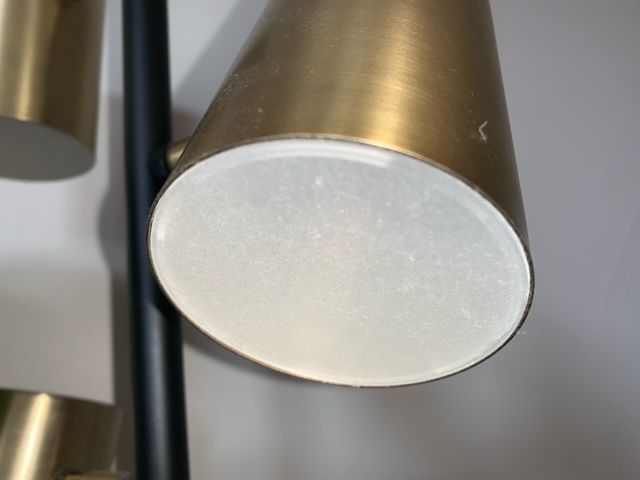 A close up of a brass lamp with a white glass shade.