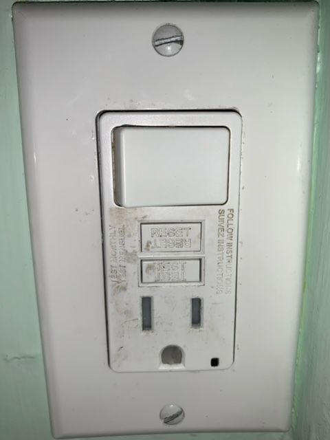 A white electrical outlet with a light switch attached to it.