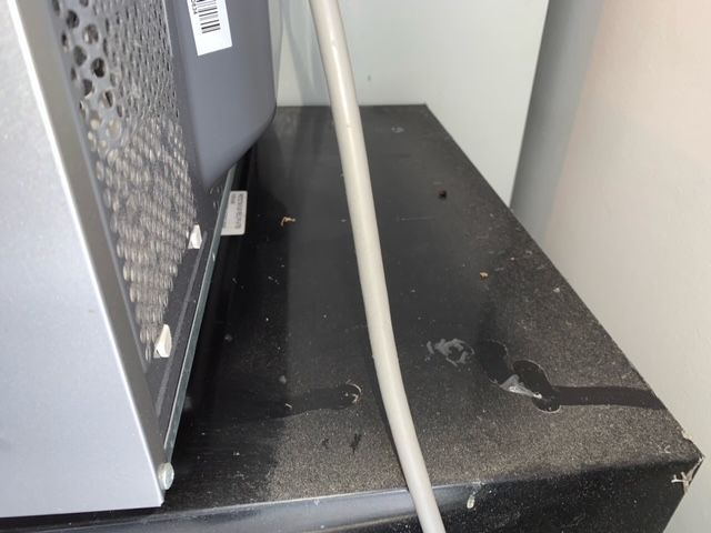 A microwave is sitting on a table with a hose attached to it