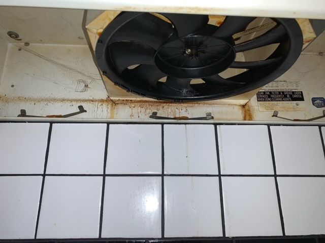 A fan is hanging from the ceiling above a tiled wall
