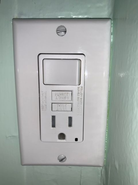 A white electrical outlet with a light switch attached to it.