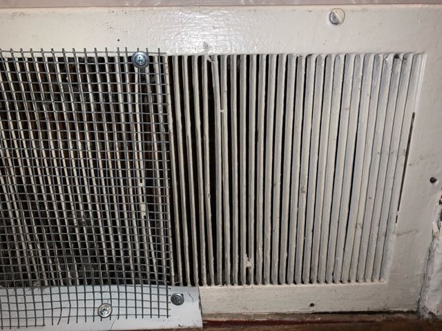 A close up of a metal grille on a wall.
