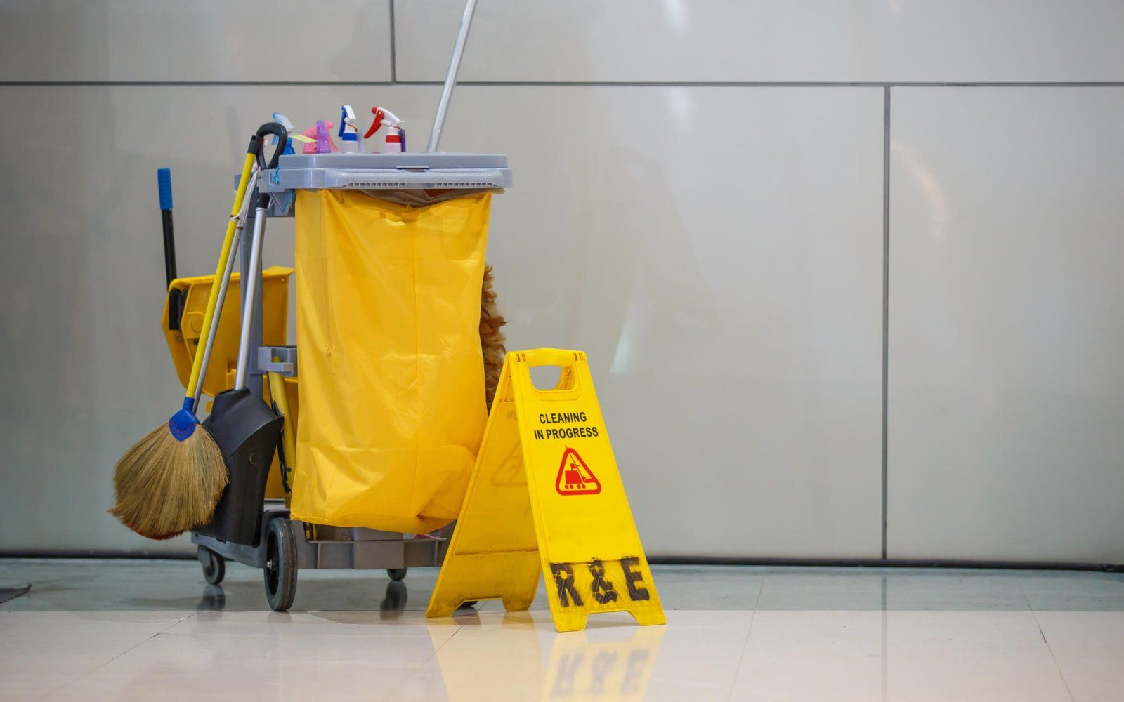 A yellow caution sign is next to a yellow cleaning cart.
