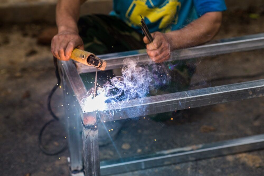 A Man is Welding a Piece of Metal With a Welding Machine — LM Engineering In Mareeba, QLD