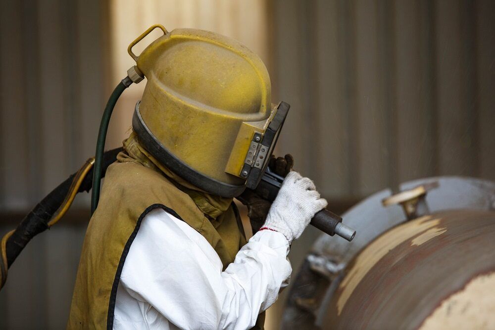 A Person Sandblasting a Rust Metal With Personal Equipment — LM Engineering In Mareeba, QLD