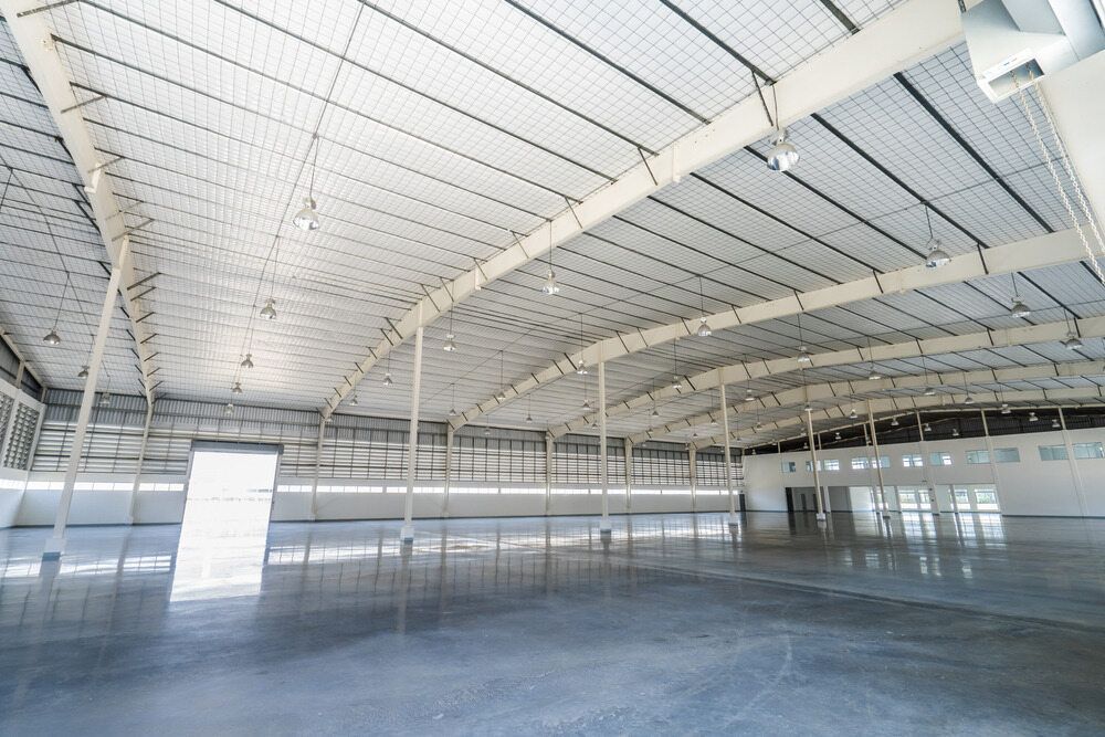An Empty Warehouse With a White Ceiling and Concrete Floor — LM Engineering In Mareeba, QLD