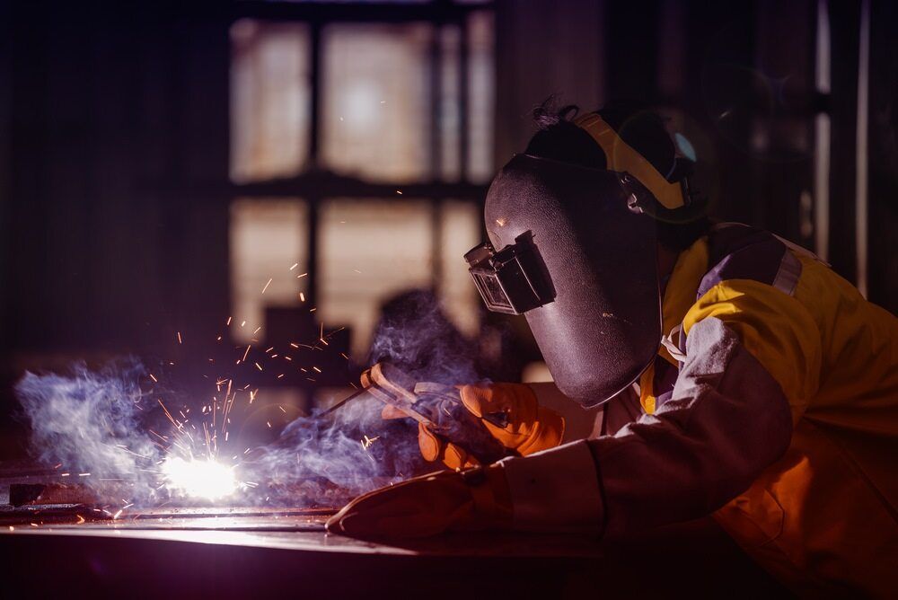A Man Wearing a Welding Mask is Welding a Piece of Metal — LM Engineering In Mareeba, QLD