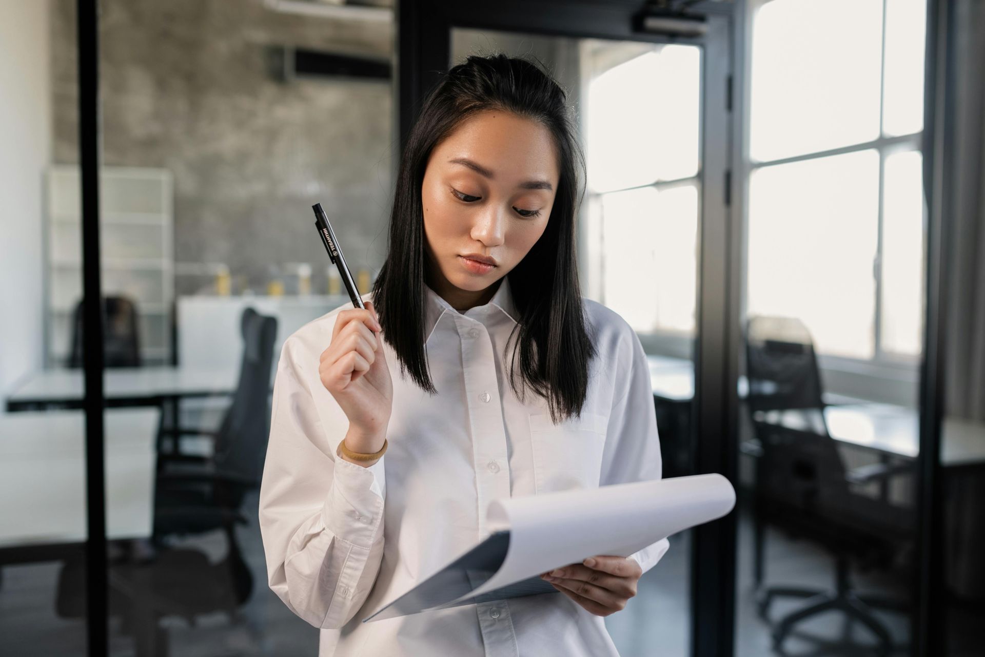 A Woman is Holding a Pen and Looking at a Piece of Paper
