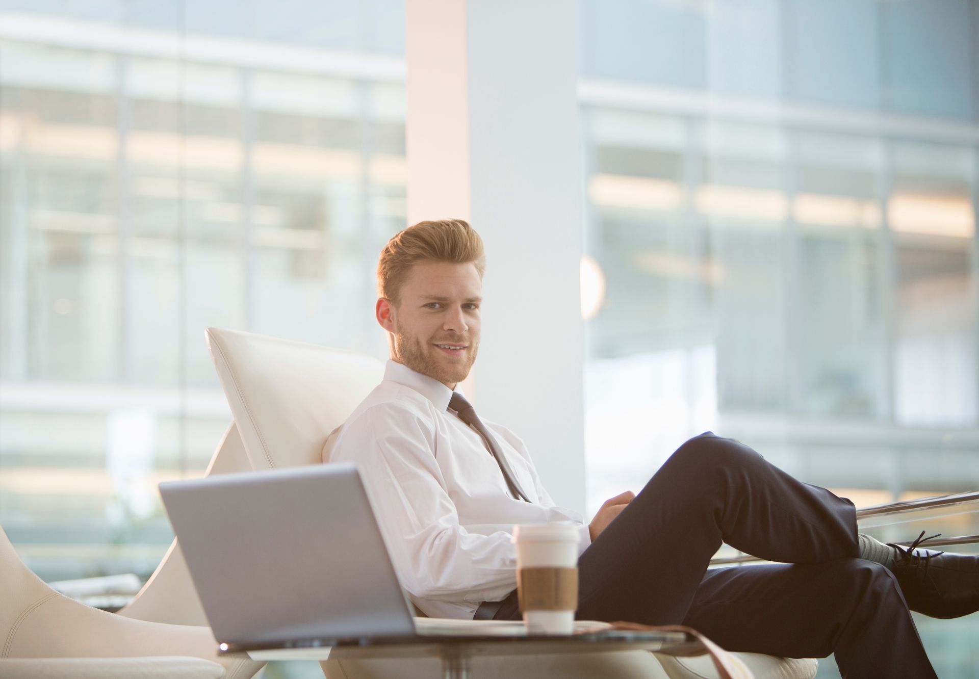 A man is sitting in a chair with his feet up and using a laptop computer.