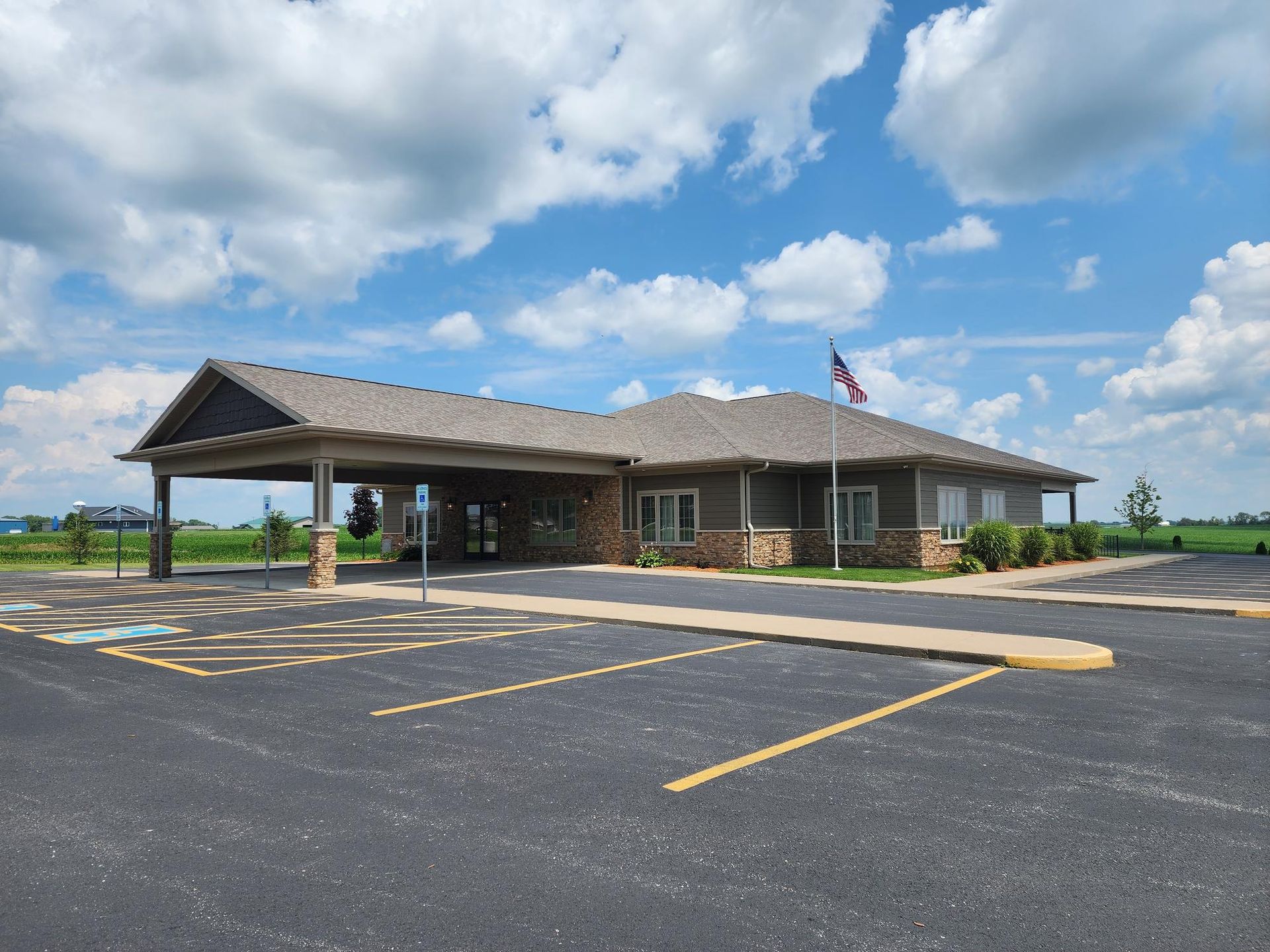 A one-story professional building with a large covered entrance, tan siding, stone accents, and an American flag outside.