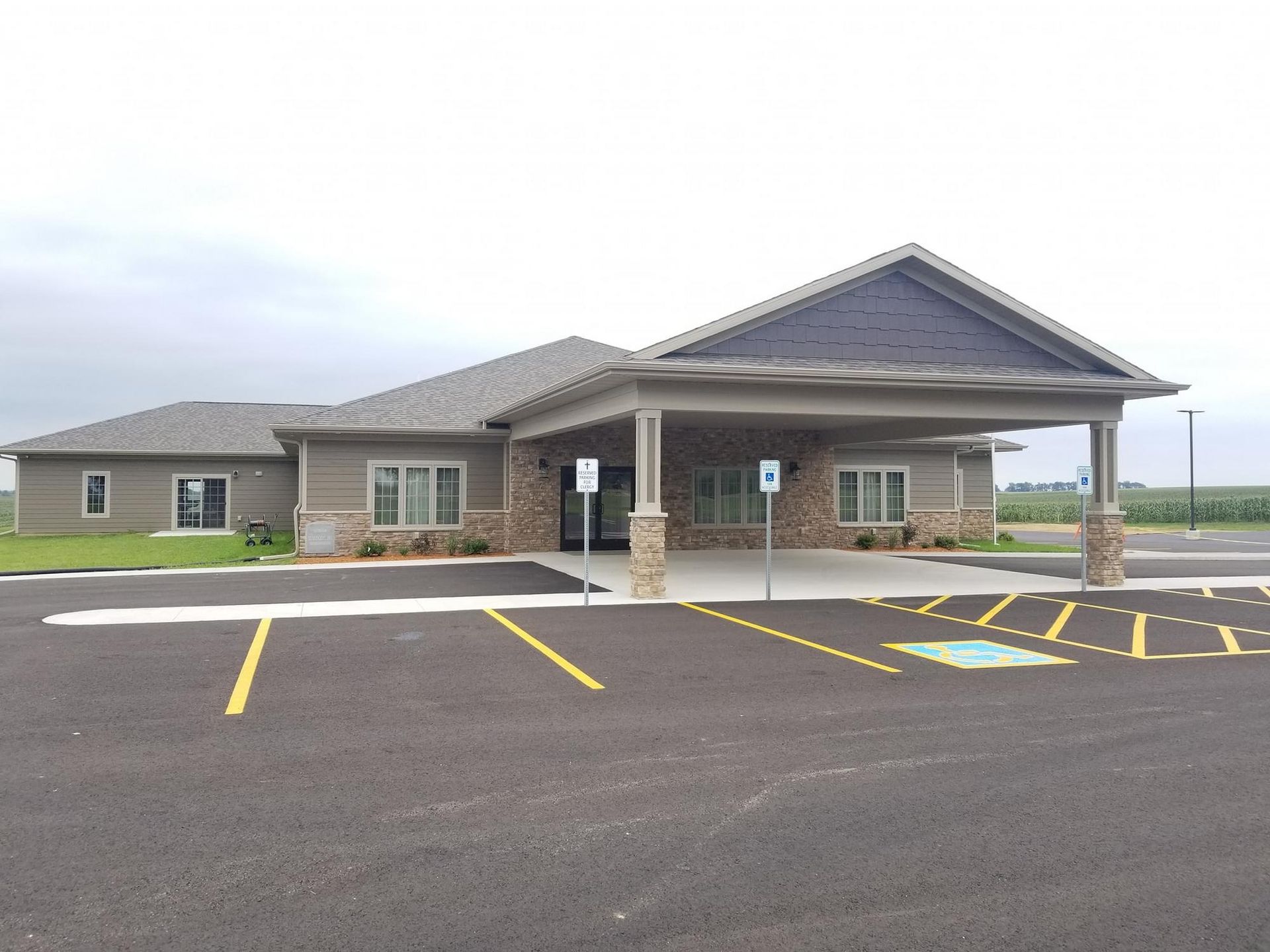 A single-story building with a covered entrance, stone facade, and paved parking lot with accessible spaces.
