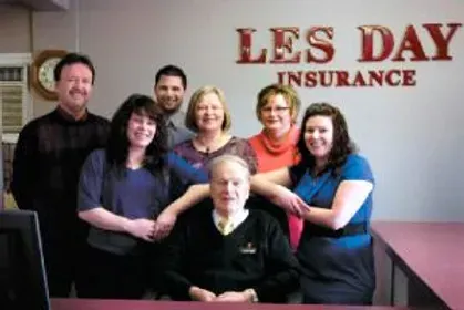 A group of people standing in front of a sign that says les day insurance