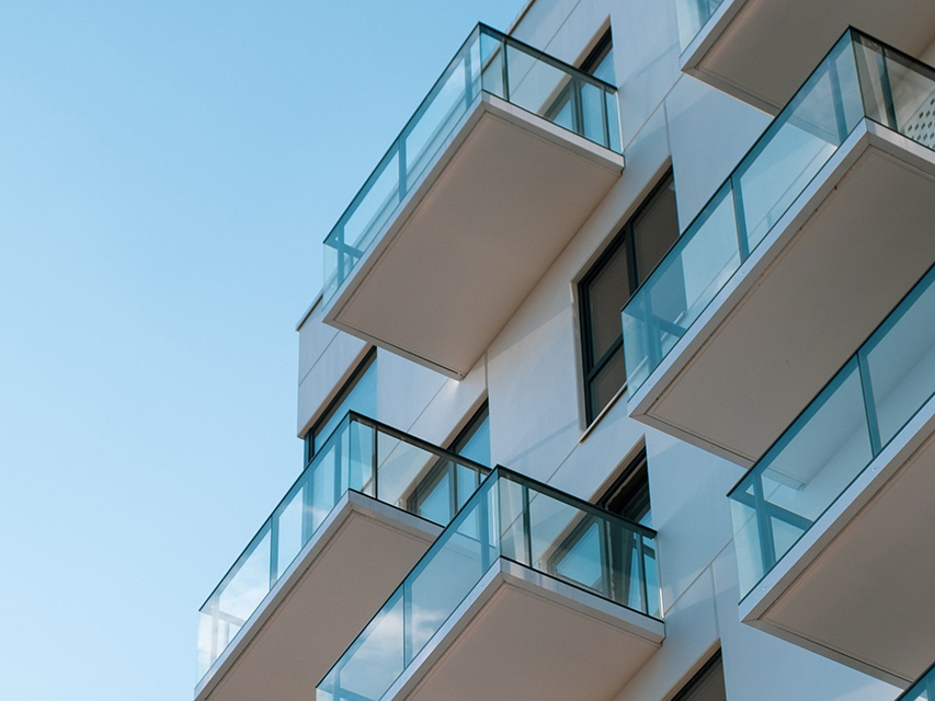 A building with a lot of balconies and windows against a blue sky.
