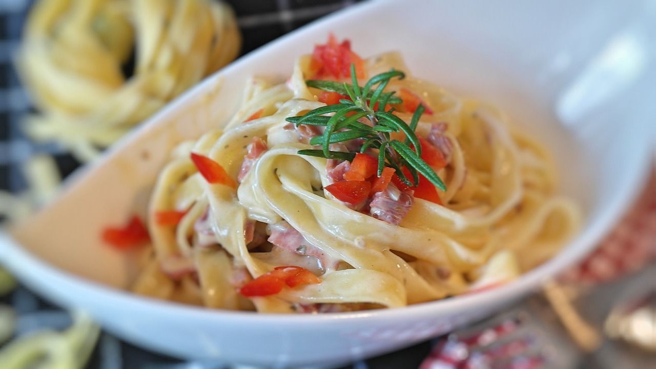 a bowl of pasta with tomatoes and rosemary on top