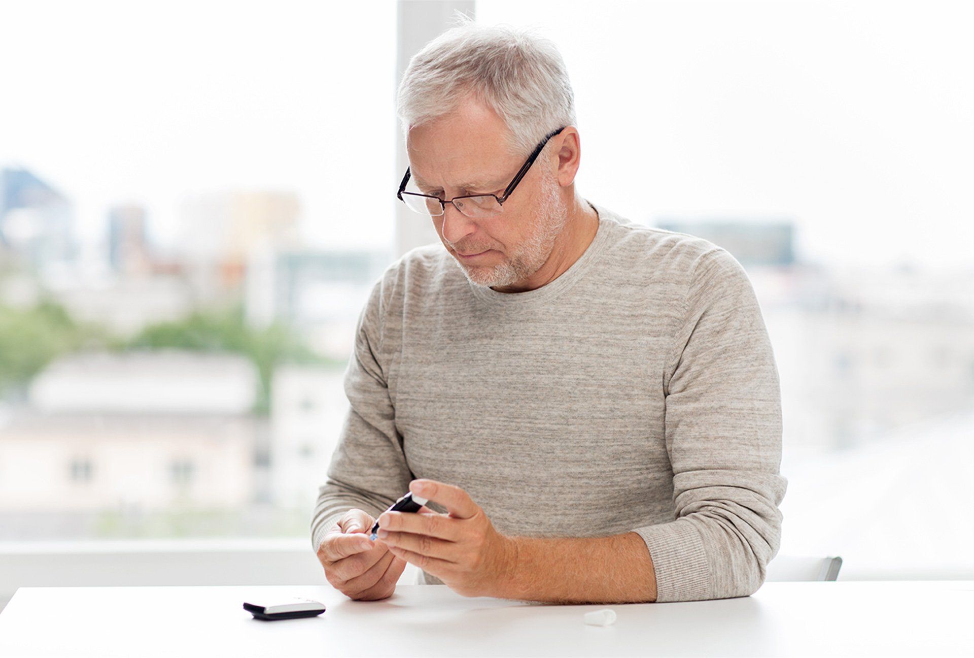medicine, age, diabetes, health care and old people concept - senior man with glucometer checking bl