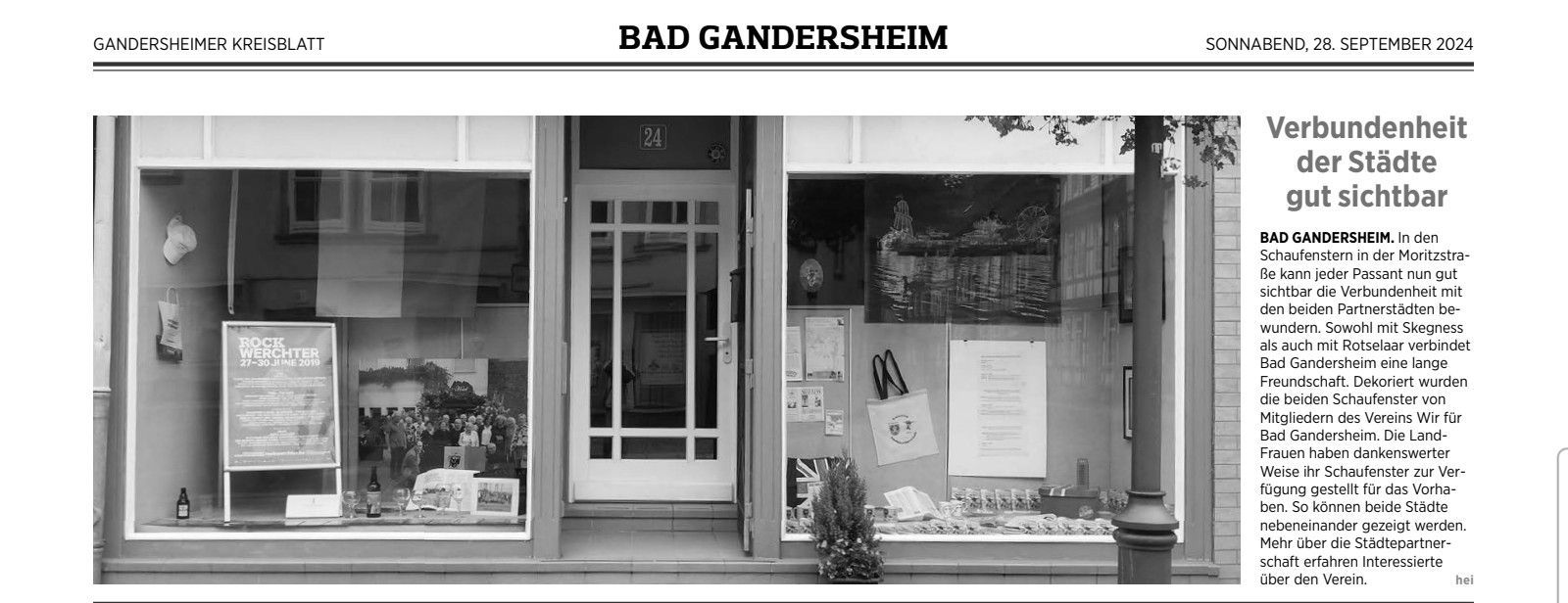Schaufenster mit ausgestellten Waren. Text ist auf den Fenstern und darüber sichtbar.