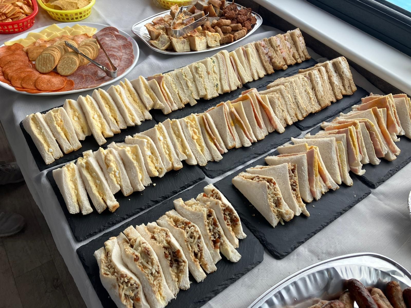 Auf einem Tisch standen belegte Brötchen und andere Speisen, darunter Würstchen im Teigmantel und Aufschnitt.