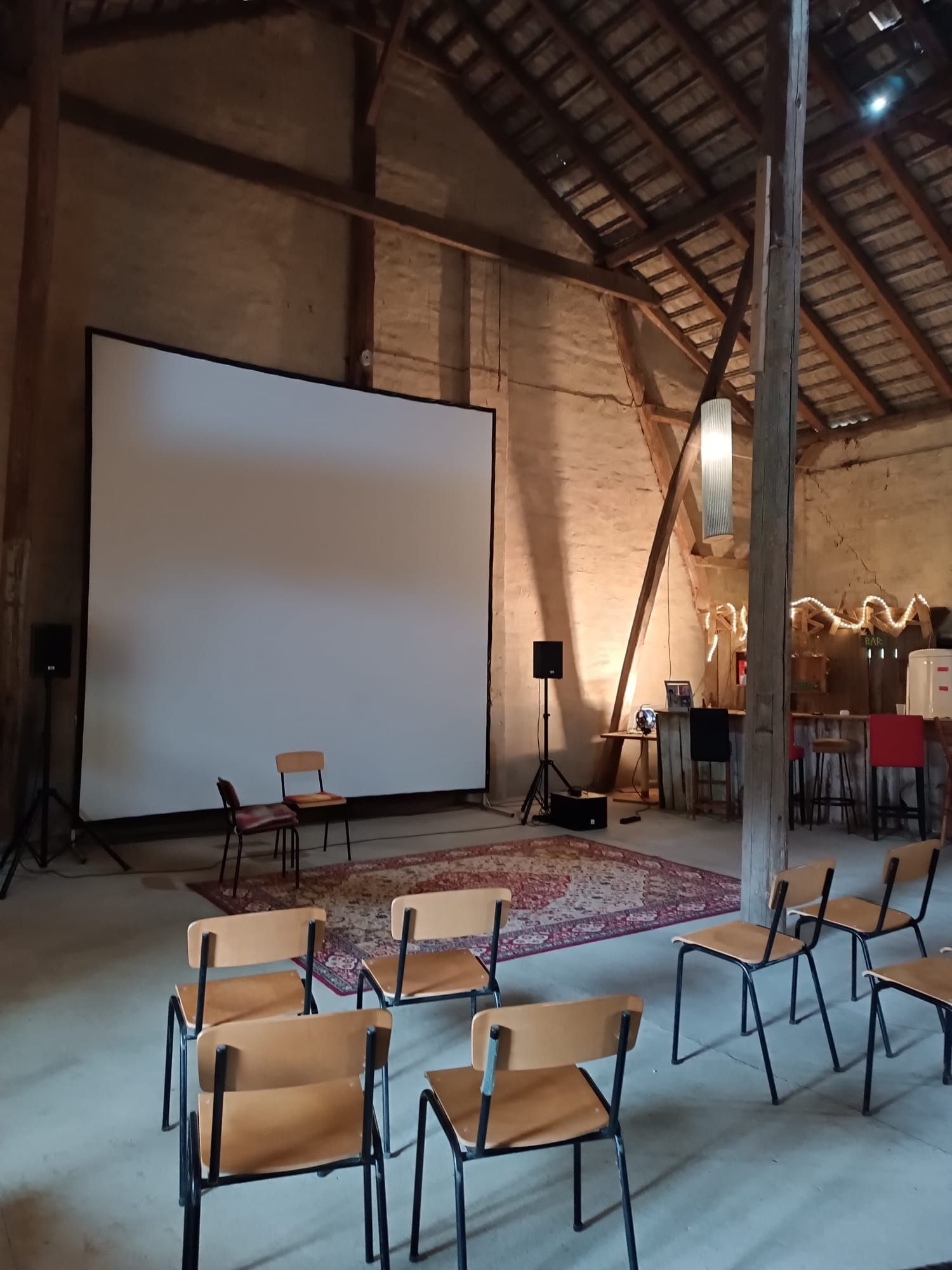 Große weiße Leinwand in einer Scheune, Stühle für eine Präsentation aufgestellt.