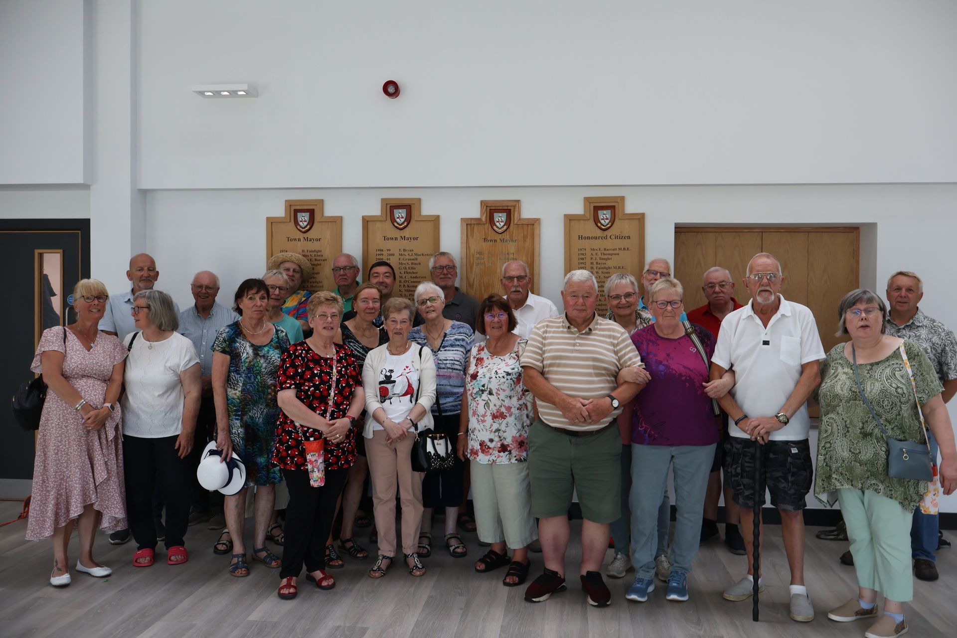 Eine Gruppe von Menschen posiert für ein Foto in einem Gebäude mit Holztafeln an der Wand.