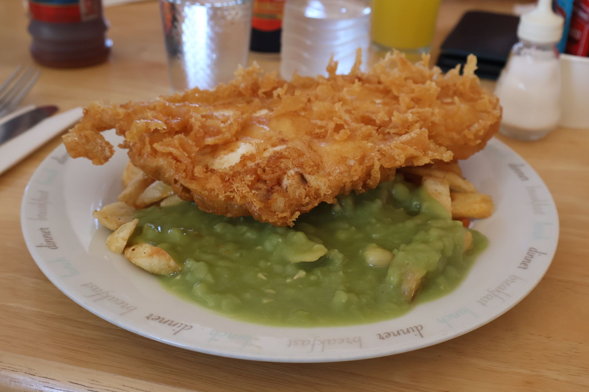 Fish and Chips mit Erbsenpüree auf einem weißen Teller; ein klassisches britisches Gericht.