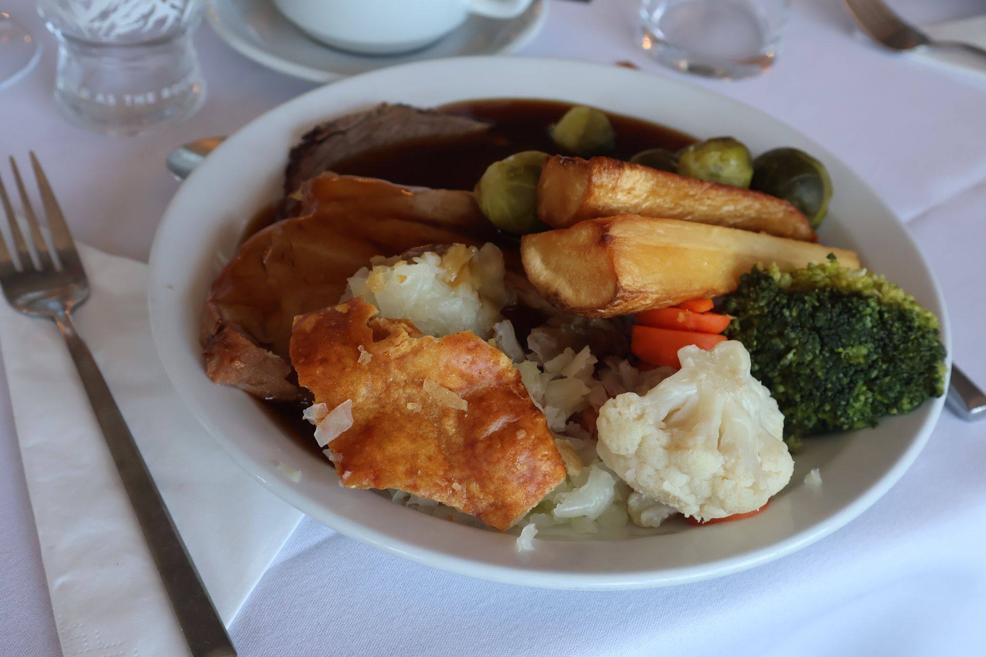 Teller mit Roastbeef, Gemüse, Yorkshire-Pudding und Bratensoße.