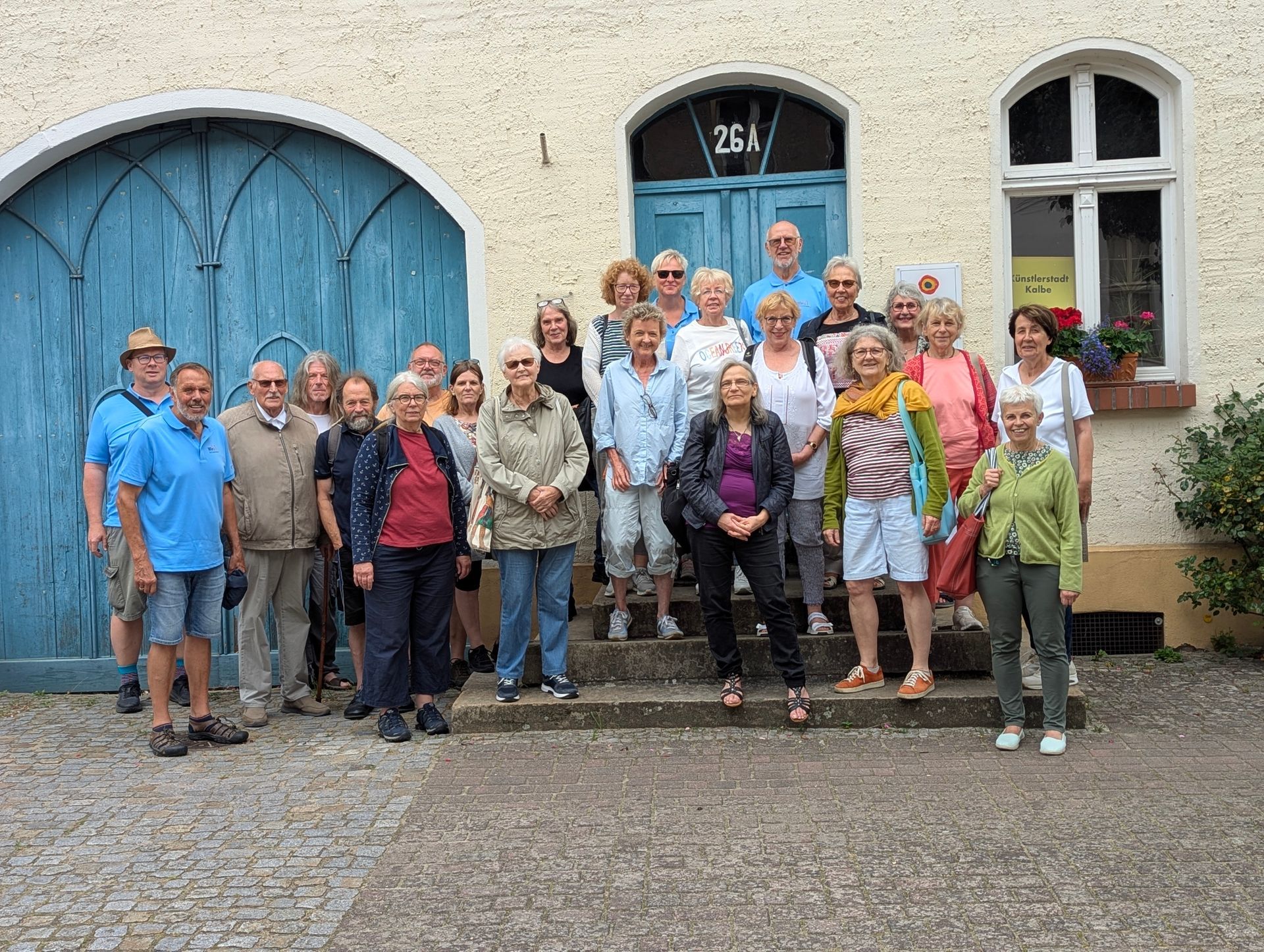 Eine Gruppe von Menschen steht auf Stufen vor einem Gebäude mit einer blauen Tür.