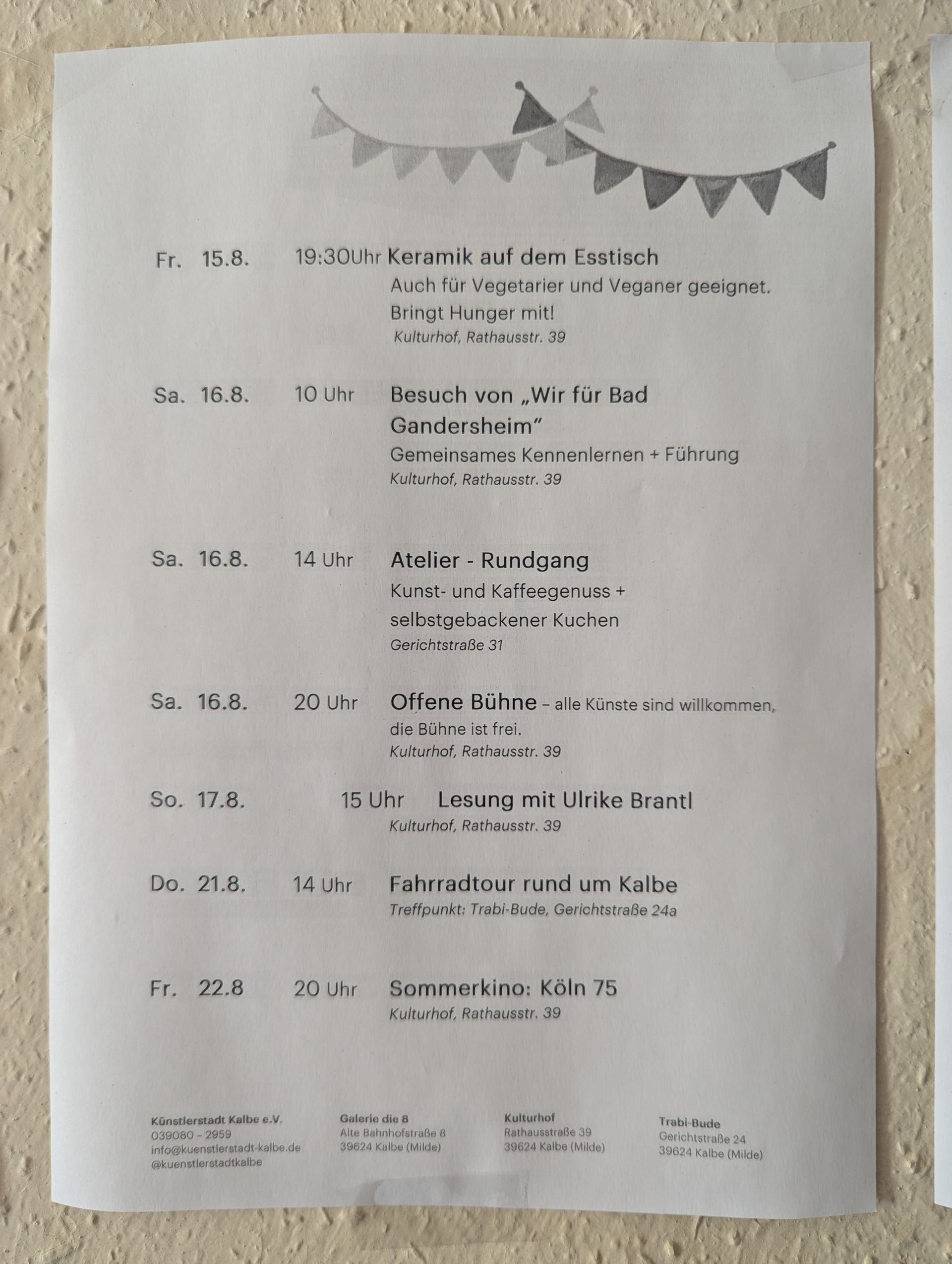Gedruckter Veranstaltungsplan mit Datum, Uhrzeit und Beschreibung sowie eine Lichterkette mit dekorativen Fähnchen.