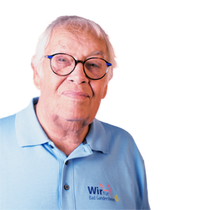 Man wearing glasses and a blue polo shirt smiles; logo reads 