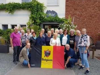 Eine Gruppe von Menschen hält eine belgische Flagge vor einem Hotel.