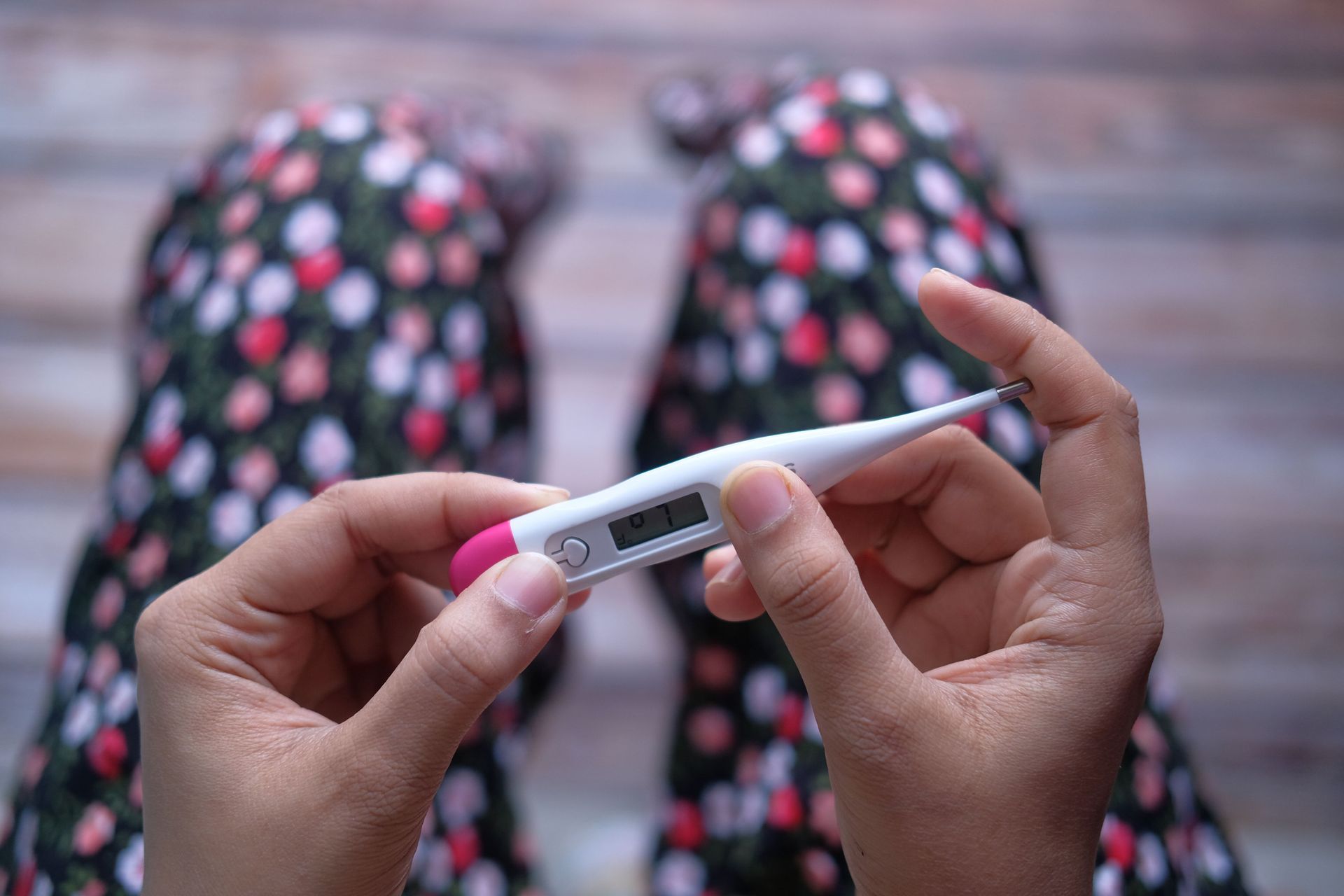 Mãos segurando um termômetro digital para medir a temperatura durante a quimioterapia