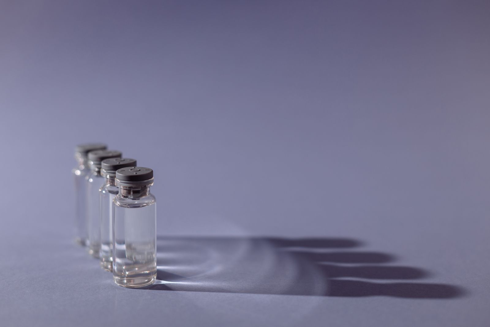 Frascos de medicamento sobre fundo lilás, ilustrando a quimioterapia