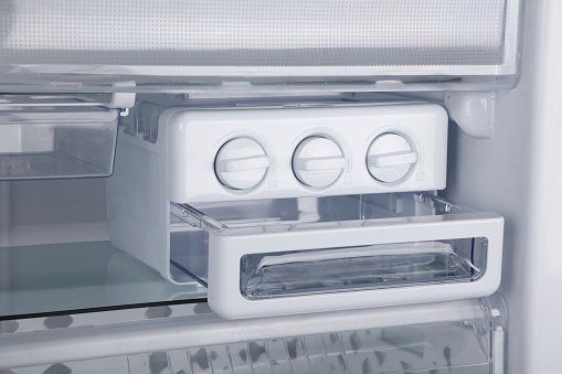 Person using a multimeter to test a washing machine's internal components. Tools and parts are visible on top.