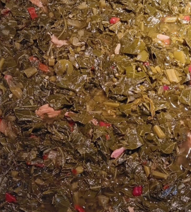 Close-up of chopped leafy vegetables in a brown broth or sauce, with scattered pink bits