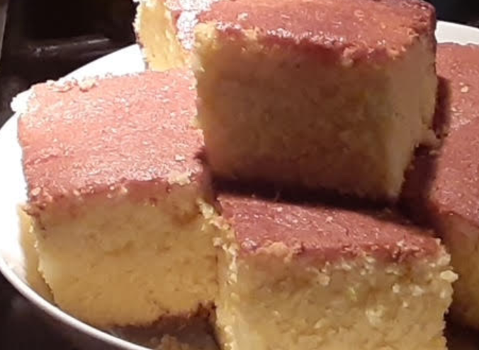 Stacked squares of golden cake with a brown sugar glaze on a white plate