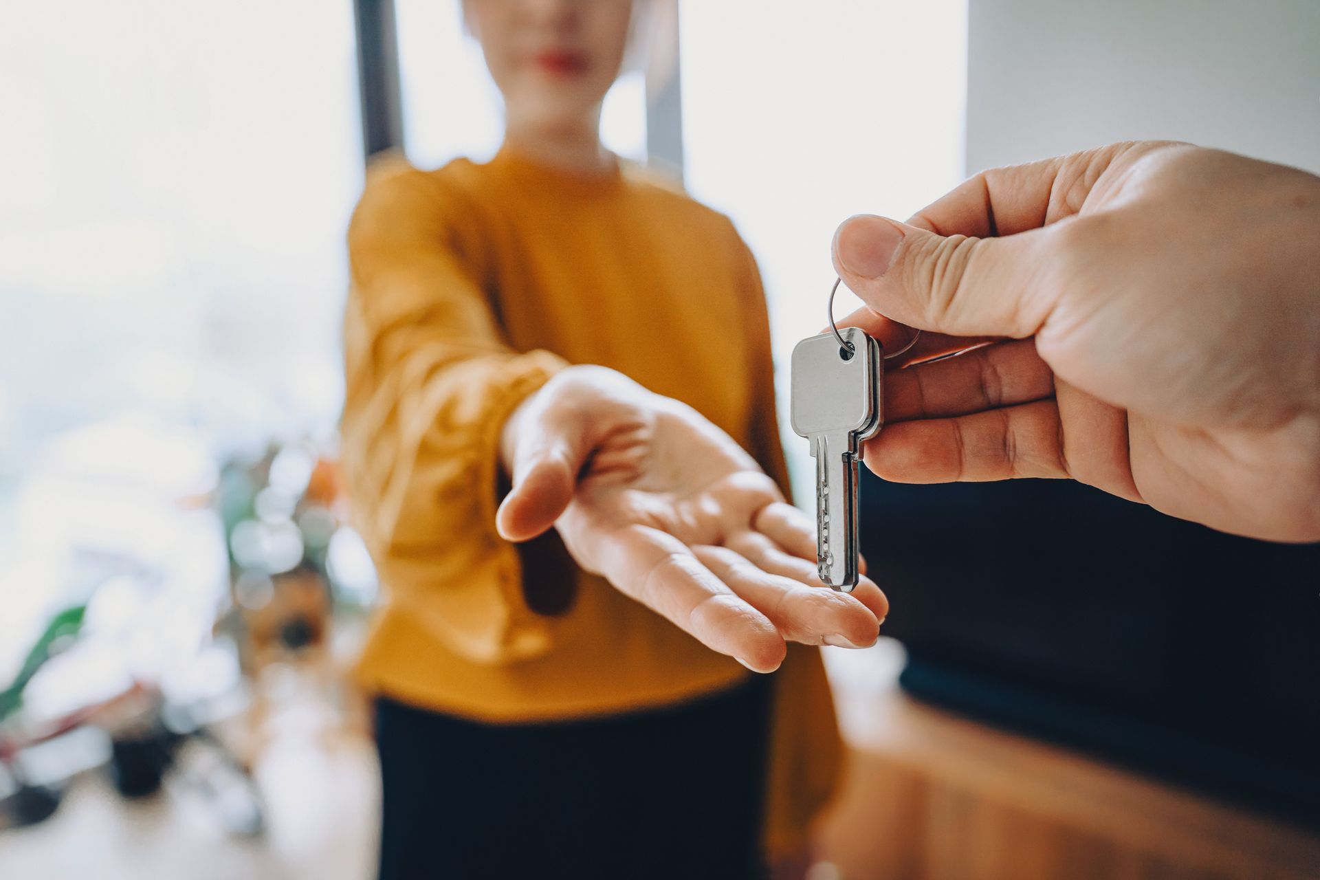 Hand passing keys to another person.