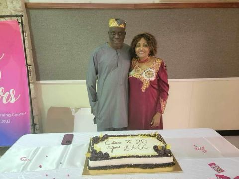 A man and a woman are standing next to a cake on a table.