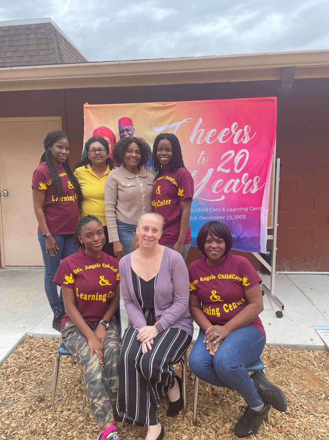 A group of women are posing for a picture in front of a sign that says cheers 20 years.