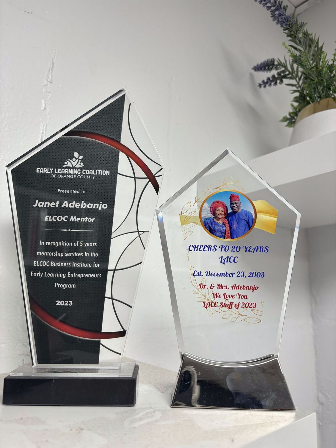 Two trophies are sitting next to each other on a table.