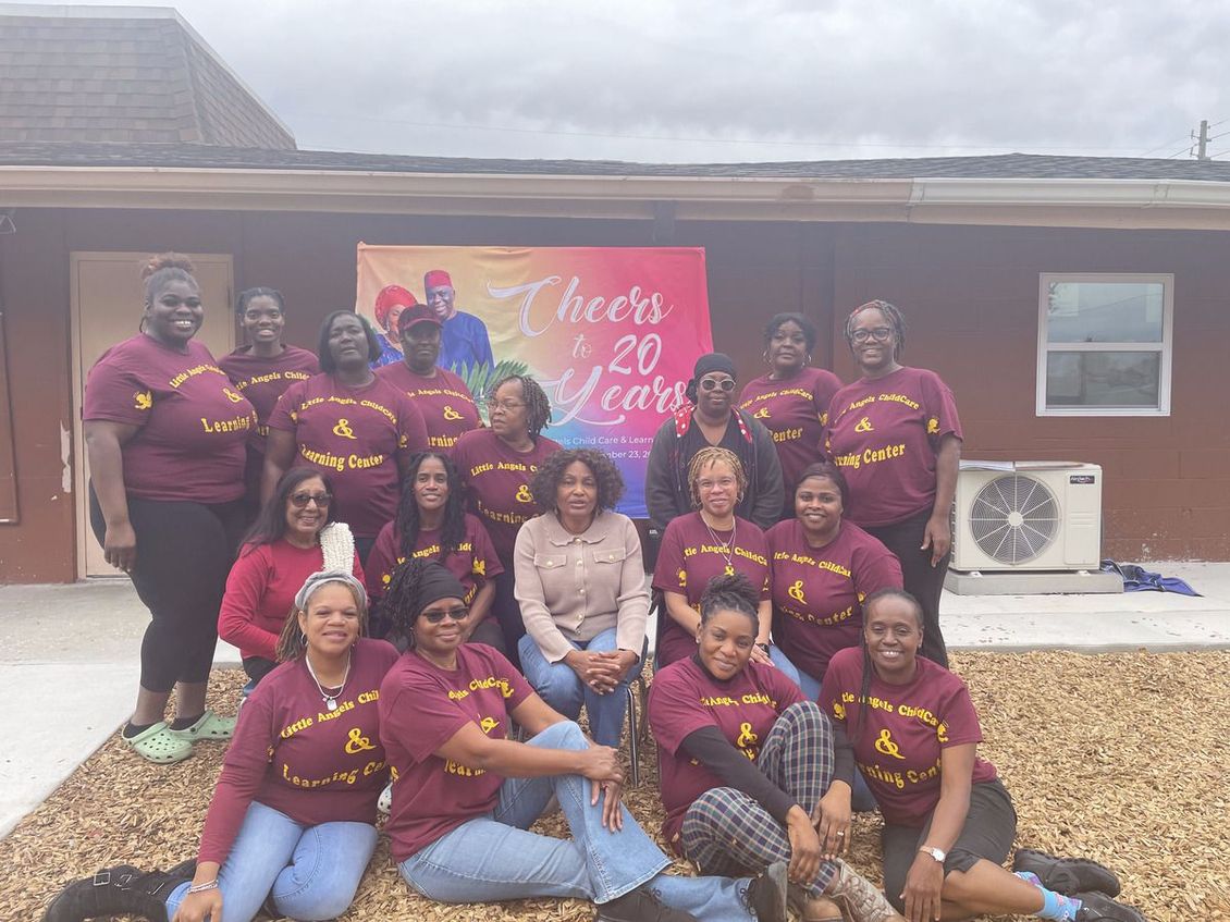 A group of women are posing for a picture in front of a house.