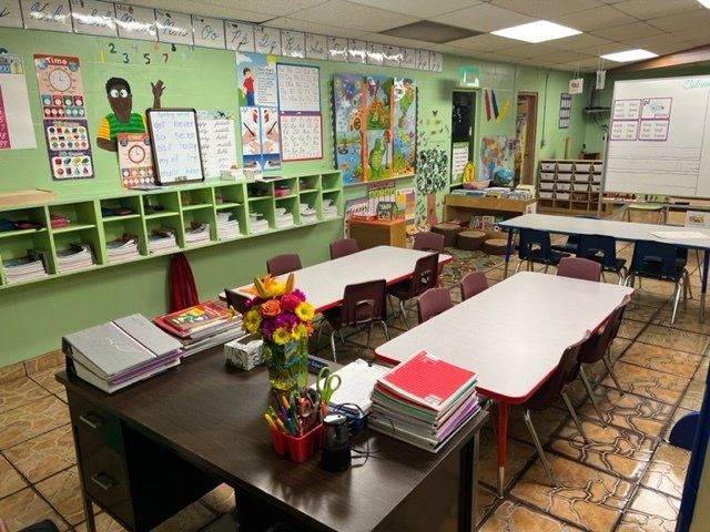 A classroom with tables and chairs and a vase of flowers on the table.