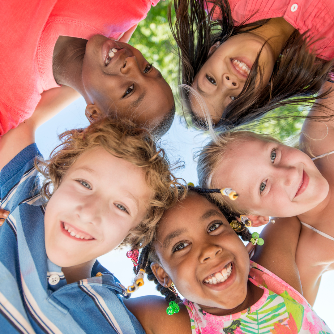 A group of children are standing in a circle and smiling for the camera