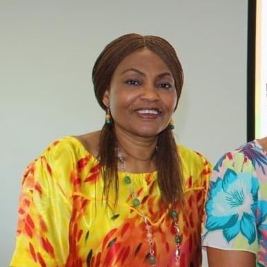 A woman in a yellow dress is smiling for the camera.
