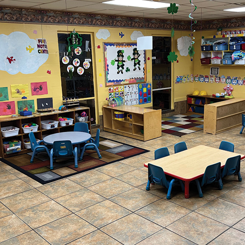 A classroom with tables and chairs and a bulletin board