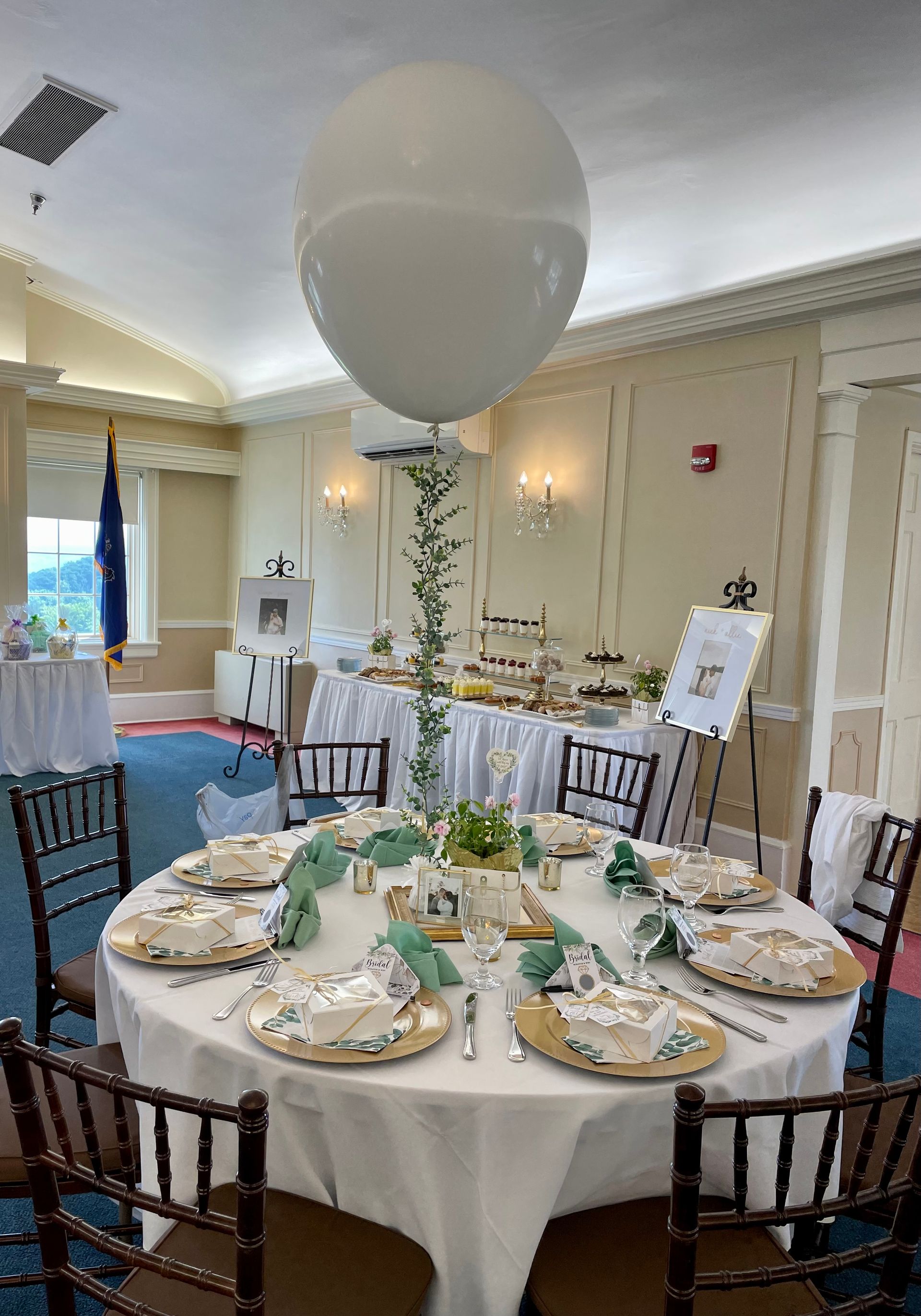 Round banquet table set with place settings and white balloon centerpiece in a decorated event hall