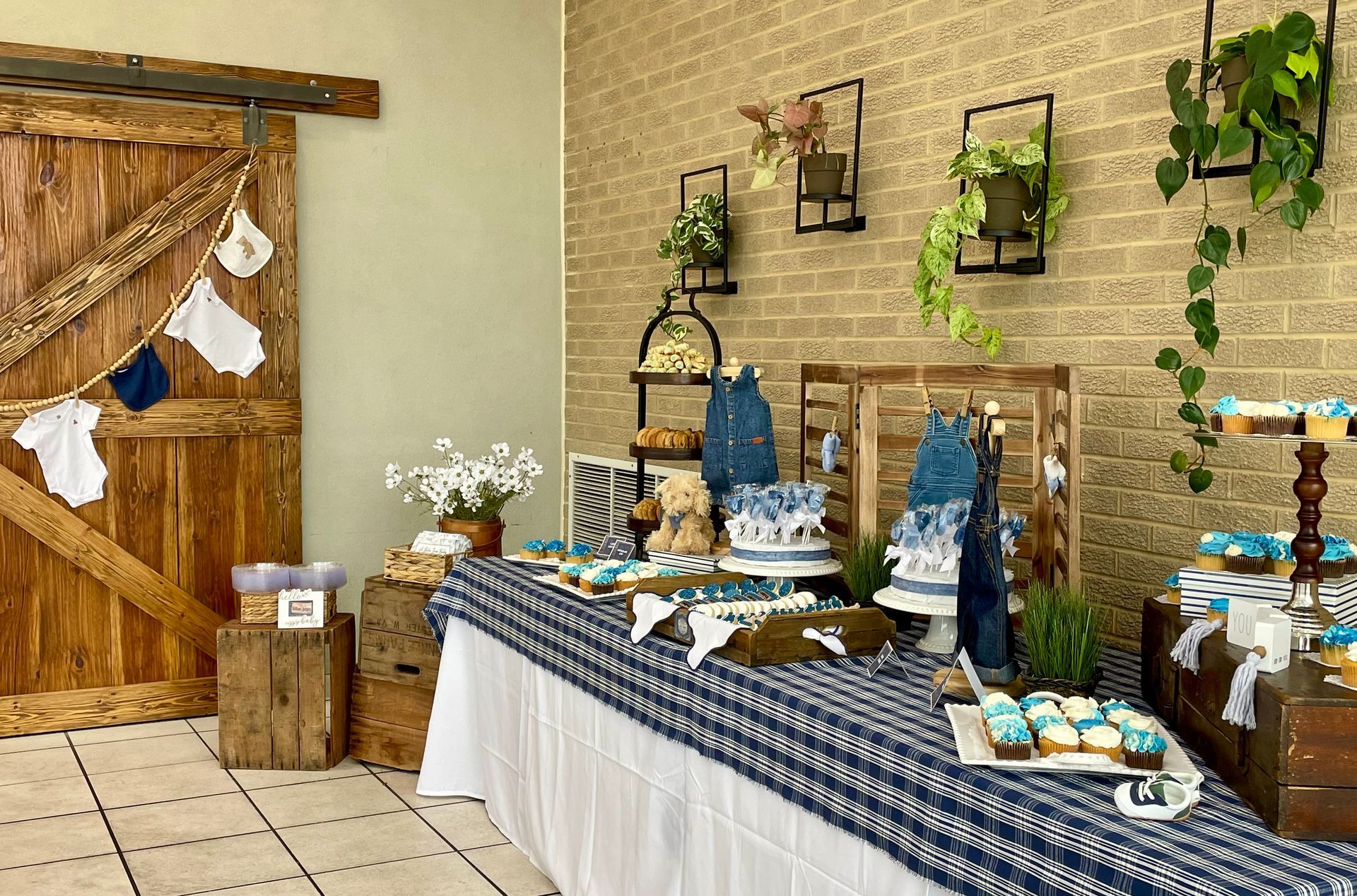 Decorated dessert table with blue and white treats, baskets, and plants in a rustic indoor setting